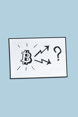 Photo of Bitcoin sign and two arrows going to up and down – hand-drown concept on white paper. The concept of future trends in bitcoin exchange rates, vertical image.
