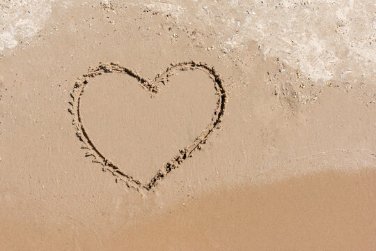 Photo of heart drawn on yellow sand Real romantic love concept..