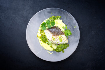 Modern Style traditioneller gebratenes Skrei Kabeljau Fisch Filet mit Kartoffel Püree Creme und Koriander Limetten Relish serviert als Draufsicht auf einem  Nordic Design Teller mit Textfreiraum