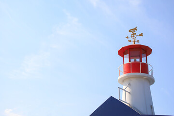 Red and white lighthouse with a blue sky in the summer - obrazy, fototapety, plakaty