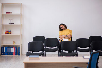 Young male student waiting for teacher in the classroom