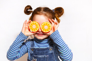 A girl with toy orange halves for eyes on a white background. Child plays with sliced plastic...