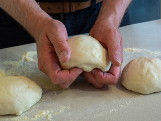 Hands kneading a ball of pizza dough