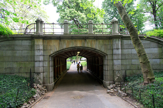 People Walking Through A Tunnel Under A Bridge In A Park In The Summer