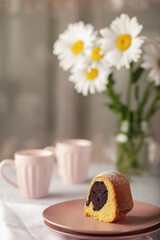 Round cupcake with a hole on a white dish, sprinkled with powdered sugar