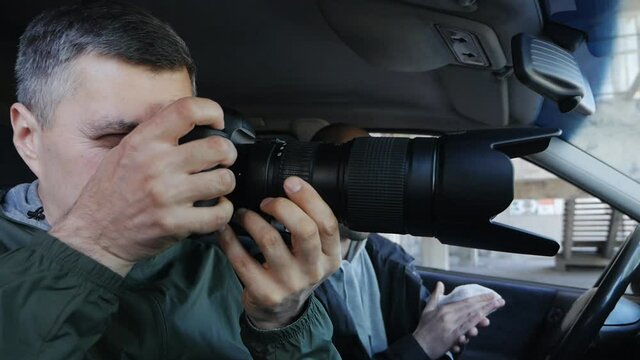 Paparazzi or detectives secretly photograph something while sitting in the car. Collecting compromising evidence or material for an article