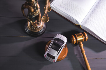 statue of justice, gavel and car on a wooden background.
