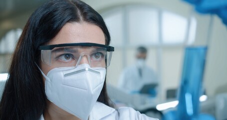 Fototapeta na wymiar Close up of Caucasian beautiful woman chemistry researcher in laboratory working testing microbiology blue liquid Young female medical scientist working on coronavirus cure looking at test tube in lab