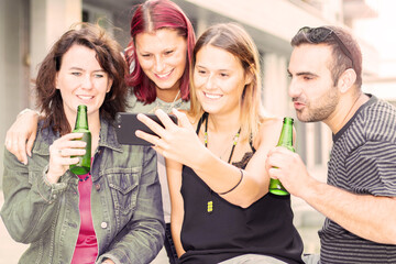 Group of smiling friends watch an tabet and drink a beer