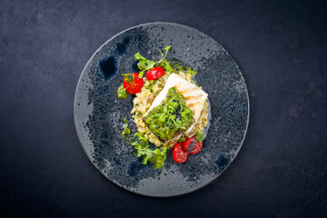 Modern style traditional fried skrei cod fish filet with mushroom rice risotto and oregano salsa...