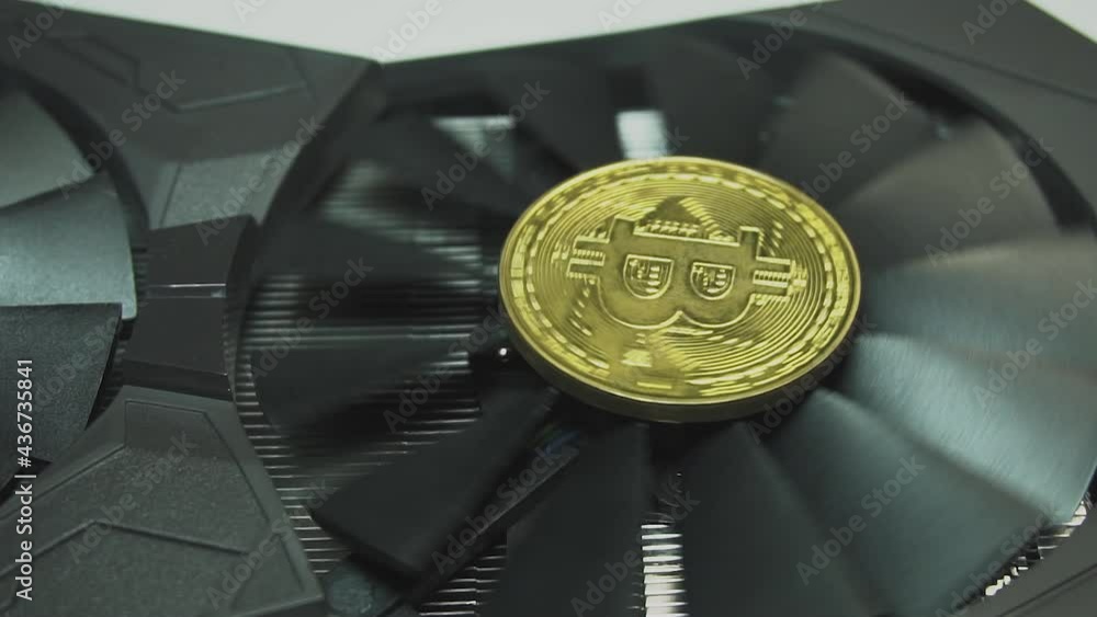 Poster cooling fans spinning on the video card, bitcoin coins shine in the light and pickaxes as a symbol o