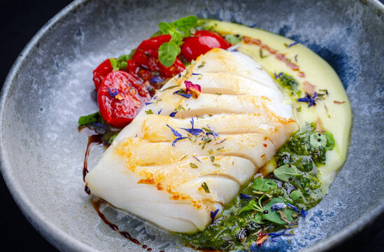 Modern style traditional fried skrei cod fish filet with mashed potato cream and coriander lime relish served as close-up on Nordic design plate 