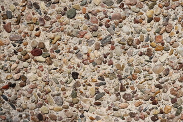Nature background - small pebbles in white sand. Texture of tiny colored stones. Detail of a stone structure.
