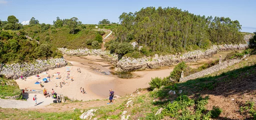Foto op Canvas Vistas panorámicas de gente tomando el sol en la Playa de Guadamia, rodeada de vegetación verde, en las vacaciones de verano de 2020 en Asturias, norte de España. © acaballero67