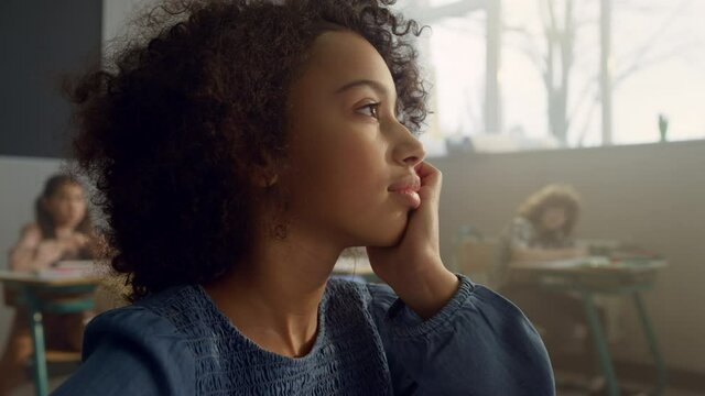 Thoughtful pupil sitting in classroom. African girl boring during lesson