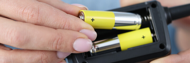 Female hands inserting batteries into remote closeup