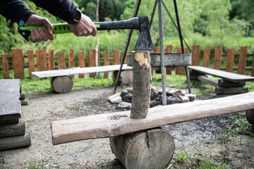 Man chops wood on a wooden pad.