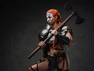 Armoured nordic woman fighter with axe on her shoulder in studio