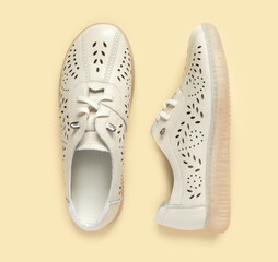 Pale white female shoes on yellow backdrop. Flat lay, top view trendy fashion feminine background.