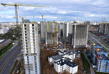 Fototapeta premium Tower crane during construction of a residential building. Cranes on formworks. Construction the building or multi-storey homes, Arial view. Renovation concept. Realtor and Real Estate