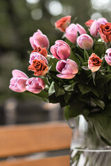 Pink roses and tulips in vase, with soft focus on the background, romantic, with dark green leaves 
