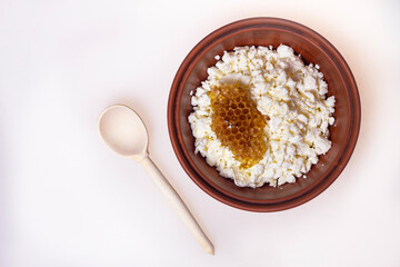 cottage cheese with honeycomb in a bowl on a table with a wooden spoon
