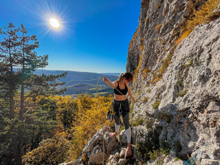 LENS FLARE: Young woman prepares the belay rope before climbing in Crni Kal.