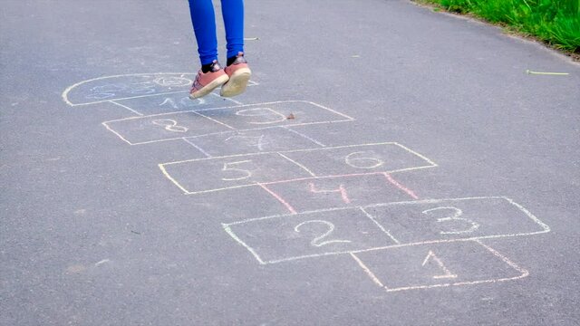 Children play classics jumping on the asphalt. Selective focus.