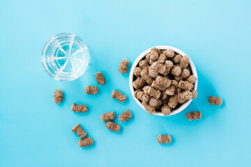 Rye bran in a bowl and on the table and a glass of water on a blue background. Diet and cleansing the body with fiber. Top view