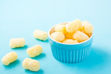 Corn sticks in powdered sugar in a bowl on a blue background. Children treat