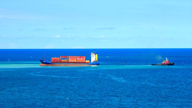 Cap-Haitien, Haiti - 01.06.2021.Tug towing grounded containership BELEN for remove from shallow water.