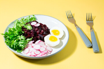 A dietary dish made from vegetables. Beet tartare, radish, frisee salad and boiled egg on a plate...