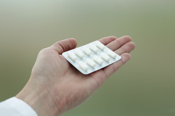 A package of white medical pills lies on the hand