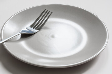 Close-up of a fork lying on an empty gray plate