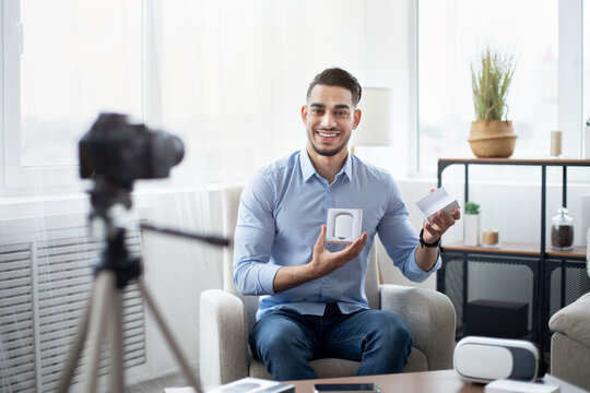 Arab Male Vlogger Making Video Review Of New Wireless Earphones, Using Professional Camera At Home