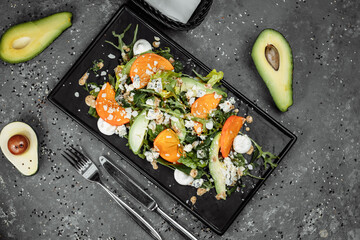 Fresh salad with fruits and greens on dark canvas background. Healthy food
