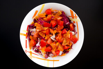 Salad with carrots and tomatoes on black table, top view