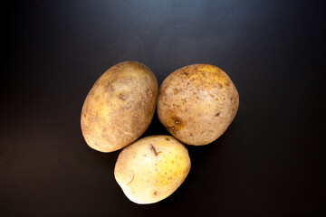Potatoes on black table, food background