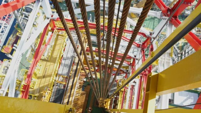 Metal cables go down. View down from Derrick. Offshore Drilling Platform. RIG. Cables swing