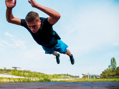 Fitness man doing clapping push-ups during outdoor cross training workout. Handsome young and fit fitness sport model training outside in park.