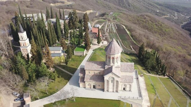 Scenic spring aerial view of monastic complex of Bodbe nunnery on hillside among tall Cypress trees with Church of St. Nino on sunny day, Sighnaghi, Georgia