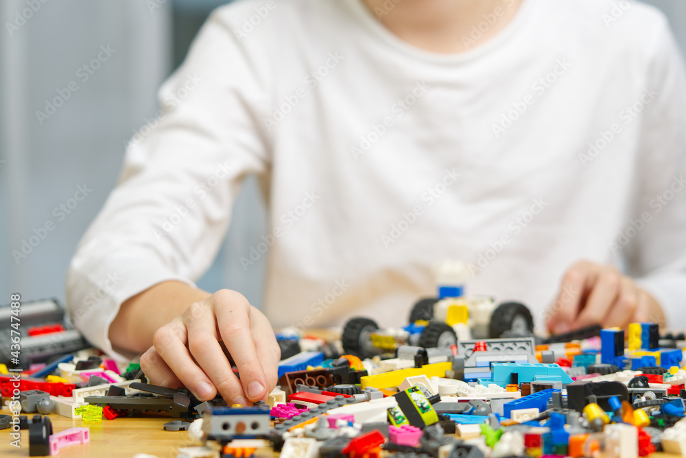 Poster close up of child's hands playing with colorful plastic bricks at the table. development of fine mot
