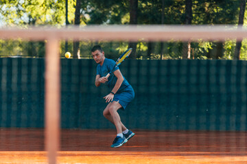 Strong male tennis player observed through the tennis net