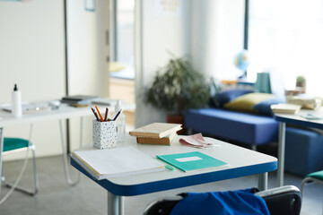 Background image of drawing desk with textbooks and supplies in school classroom interior, copy space