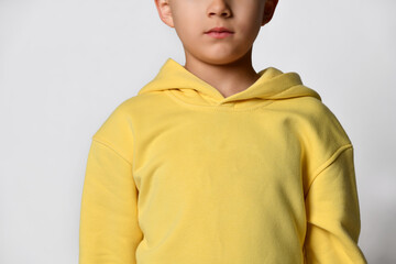 Fototapeta premium Close up detail of a yellow little boy sweatshirt. White background. Details of clothes for boys, sports suit for a student. Children's fashion concept. Place for your text. Banner.