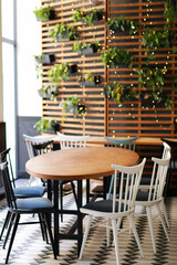 A small round table with chairs near the wall with flowerpots, home interior design