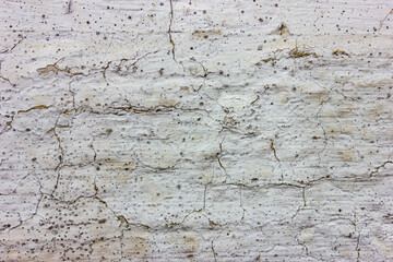 On a panel house, old white paint is peeling and cracking.