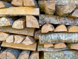 A lot of wooden logs and logs cooked for the winter in a wood-burning stove to light the fireplace...