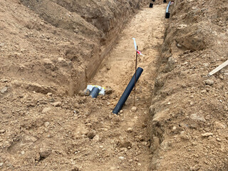 Large industrial modern new large diameter polyethylene plastic water pipes lie in a pit...