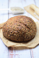 Multigrain bread, on kraft paper bag on a light colored rustic table.
Copy space.